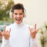 Young caucasian man at outdoors listening music making rock gesture