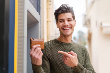 Photo for Young caucasian man at outdoors using an ATM - Royalty Free Image