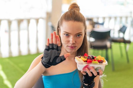 Téléchargez les photos : Jeune jolie fille sportive tenant un bol de fruits à l'extérieur - en image libre de droit