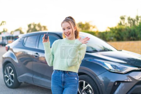 Foto de Joven chica bonita sosteniendo las llaves del coche al aire libre señala el dedo en usted con una expresión de confianza - Imagen libre de derechos