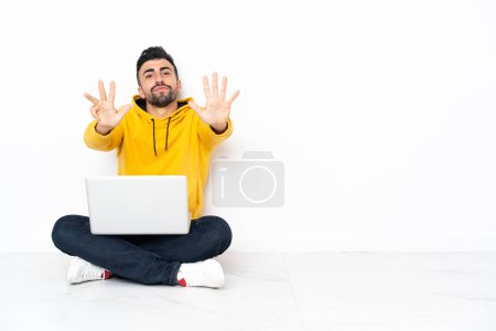 Téléchargez les photos : Blanc assis sur le sol avec son ordinateur portable comptant neuf avec des doigts - en image libre de droit