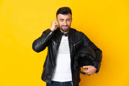 Téléchargez les photos : Homme caucasien avec un casque de moto sur fond jaune isolé frustré et couvrant les oreilles - en image libre de droit