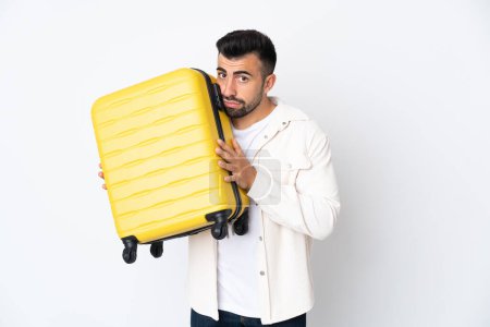 Photo for Caucasian man over isolated white background in vacation with travel suitcase and unhappy - Royalty Free Image
