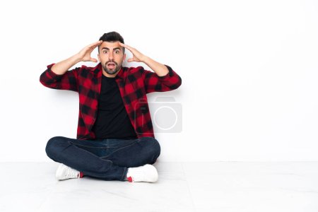 Photo for Young handsome man sitting on the floor with surprise expression - Royalty Free Image