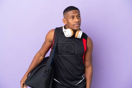 Photo for Young sport latin man with sport bag isolated  on purple background thinking an idea while looking up - Royalty Free Image
