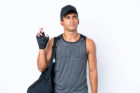 Photo for Young sport caucasian man with sport bag isolated on white background with fingers crossing and wishing the best - Royalty Free Image