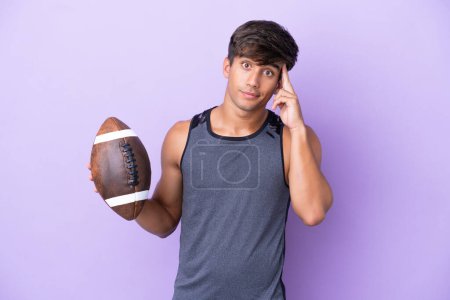 Téléchargez les photos : Jeune homme jouant au rugby isolé sur fond violet penser une idée - en image libre de droit