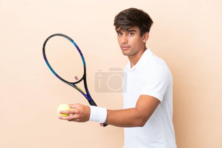 Téléchargez les photos : Jeune homme caucasien isolé sur fond ocre jouer au tennis - en image libre de droit