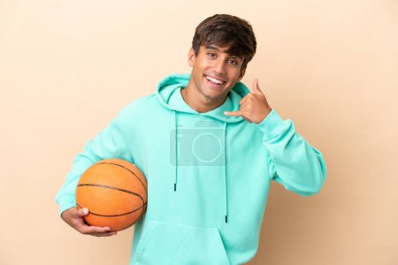 Photo for Handsome young basketball player man isolated on ocher background making phone gesture. Call me back sign - Royalty Free Image