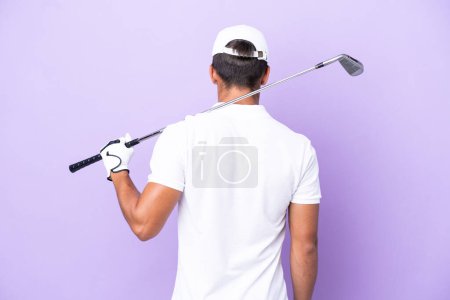 Foto de Joven hombre caucásico aislado sobre fondo púrpura jugando al golf y en la posición trasera - Imagen libre de derechos