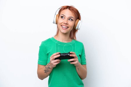 Téléchargez les photos : Jeune fille russe jouer avec un contrôleur de jeu vidéo isolé sur fond blanc penser une idée tout en levant les yeux - en image libre de droit
