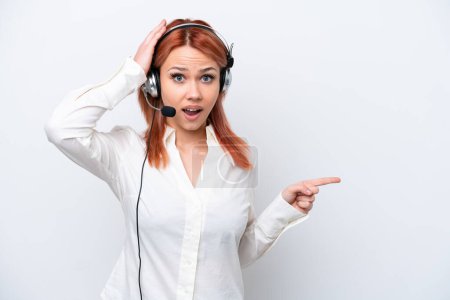 Photo for Telemarketer Russian girl working with a headset isolated on white background surprised and pointing finger to the side - Royalty Free Image