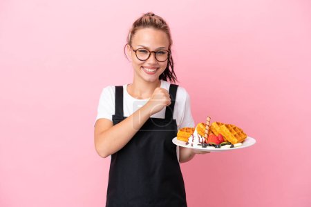 Photo for Restaurant waiter Russian girl holding waffles isolated on pink background celebrating a victory - Royalty Free Image