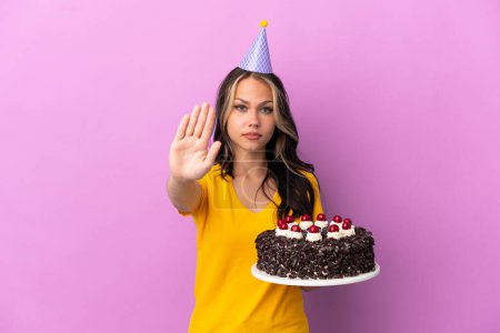 Téléchargez les photos : Adolescente russe fille tenant gâteau d'anniversaire isolé sur fond violet faisant geste d'arrêt - en image libre de droit