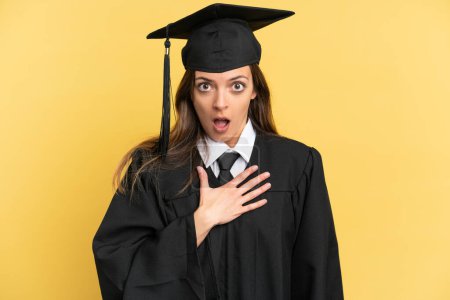 Téléchargez les photos : Jeune diplômé isolé sur fond jaune surpris et choqué en regardant à droite - en image libre de droit