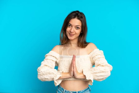Photo for Young caucasian woman isolated on blue background keeps palm together. Person asks for something - Royalty Free Image