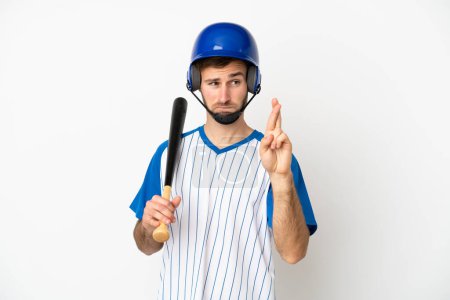 Téléchargez les photos : Jeune homme caucasien jouant au baseball isolé sur fond blanc avec les doigts croisés et souhaitant le meilleur - en image libre de droit