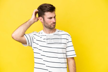 Photo for Young caucasian man isolated on yellow background having doubts while scratching head - Royalty Free Image