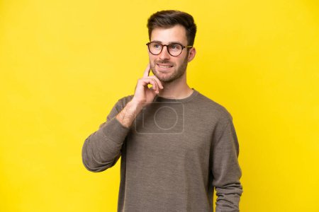 Photo for Young caucasian man isolated on yellow background thinking an idea while looking up - Royalty Free Image