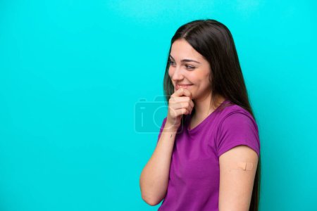 Photo for Young girl with band-aids isolated on blue background thinking an idea and looking side - Royalty Free Image