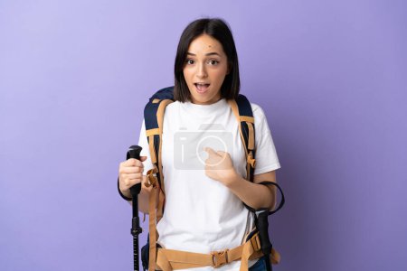 Photo for Young caucasian woman with backpack and trekking poles isolated on blue background with surprise facial expression - Royalty Free Image