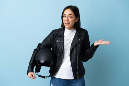 Photo for Woman holding a motorcycle helmet isolated on blue background with shocked facial expression - Royalty Free Image