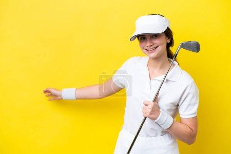 Téléchargez les photos : Jeune femme caucasienne jouer au golf isolé sur fond jaune étendant les mains sur le côté pour inviter à venir - en image libre de droit