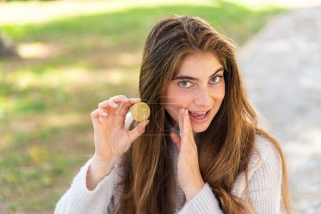 Photo for Young pretty caucasian woman holding a Bitcoin at outdoors whispering something - Royalty Free Image