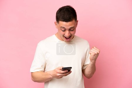 Photo for Young Brazilian man isolated on pink background surprised and sending a message - Royalty Free Image