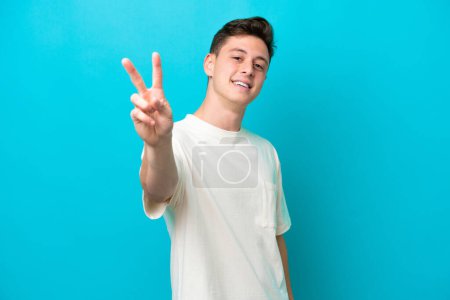 Foto de Young handsome Brazilian man isolated on blue background smiling and showing victory sign - Imagen libre de derechos