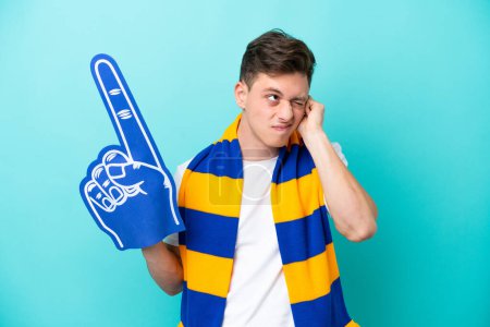 Téléchargez les photos : Jeune fan de sport homme isolé sur fond bleu frustré et couvrant les oreilles - en image libre de droit