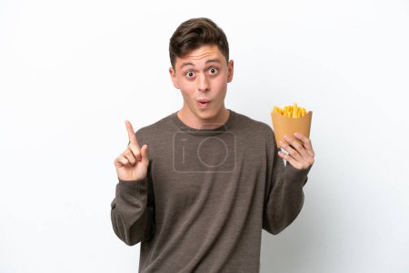 Foto de Joven brasileño sosteniendo chips fritos aislados sobre fondo blanco con la intención de realizar la solución mientras levanta un dedo - Imagen libre de derechos