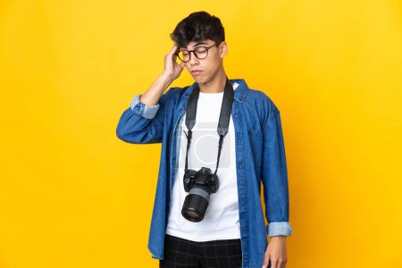 Téléchargez les photos : Jeune photographe homme sur fond jaune isolé avec mal de tête - en image libre de droit