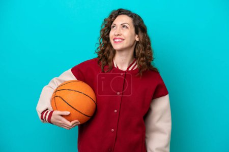Téléchargez les photos : Young caucasian basketball player woman isolated on blue background thinking an idea while looking up - en image libre de droit