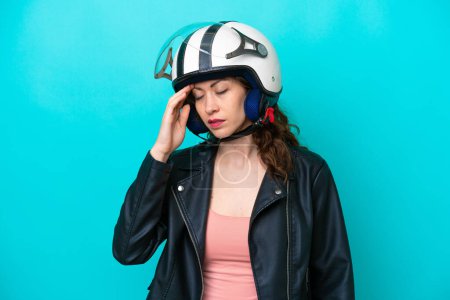 Téléchargez les photos : Jeune femme caucasienne avec un casque de moto isolé sur fond bleu avec mal de tête - en image libre de droit