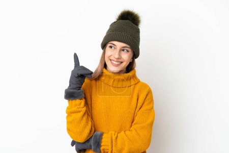 Téléchargez les photos : Jeune fille avec chapeau d'hiver isolé sur fond blanc pointant vers le haut d'une excellente idée - en image libre de droit