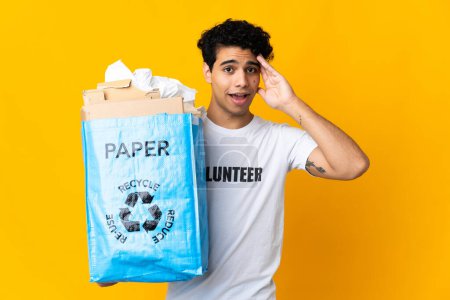 Foto de Joven venezolano sosteniendo una bolsa de reciclaje llena de papel para reciclar con expresión sorpresa - Imagen libre de derechos