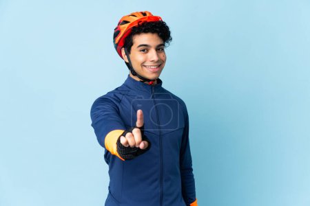 Téléchargez les photos : Vénézuélien cycliste homme isolé sur fond bleu montrant et levant un doigt - en image libre de droit