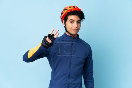Foto de Venezolano ciclista hombre aislado sobre fondo azul feliz y contando tres con los dedos - Imagen libre de derechos