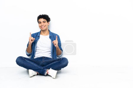 Photo for Venezuelan man sitting on the floor pointing up a great idea - Royalty Free Image