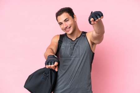 Téléchargez les photos : Jeune homme caucasien de sport avec sac de sport isolé sur fond rose pointe doigt à vous tout en souriant - en image libre de droit