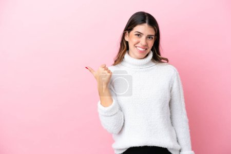 Téléchargez les photos : Jeune femme italienne isolée sur fond rose pointant vers le côté pour présenter un produit - en image libre de droit