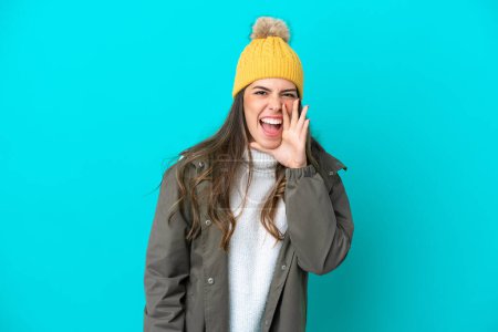 Photo for Young Italian woman wearing winter jacket and hat isolated on blue background shouting with mouth wide open - Royalty Free Image
