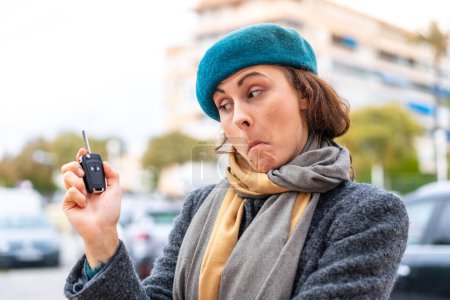 Téléchargez les photos : Brunette femme tenant des clés de voiture à l'extérieur avec une expression triste - en image libre de droit