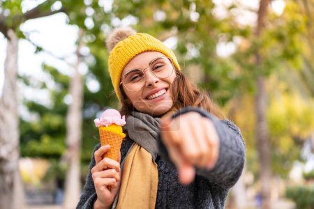 Foto de Mujer morena con un helado de corneta al aire libre te señala con el dedo con una expresión segura - Imagen libre de derechos