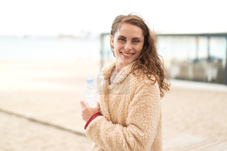 Foto de Joven mujer caucásica con una botella de agua al aire libre sonriendo mucho - Imagen libre de derechos