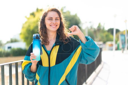 Téléchargez les photos : Jeune femme sportive avec une bouteille d'eau sportive à l'extérieur fière et auto-satisfaite - en image libre de droit