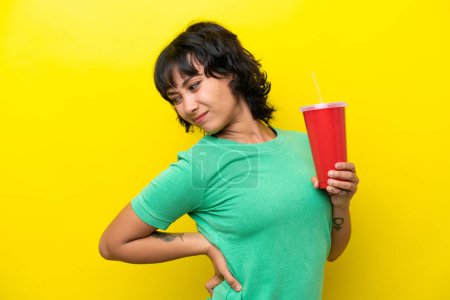 Téléchargez les photos : Jeune femme argentine tenant un soda isolé sur fond jaune souffrant de maux de dos pour avoir fait un effort - en image libre de droit