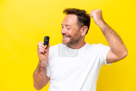 Photo for Middle age caucasian man holding car keys isolated on yellow background celebrating a victory - Royalty Free Image