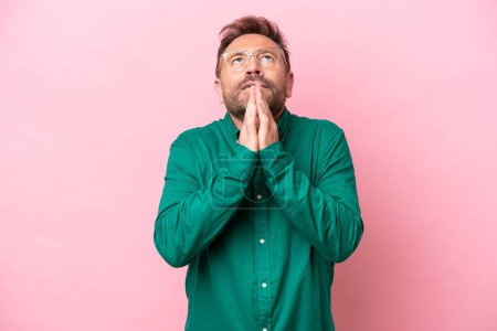 Photo for Middle age caucasian man isolated on pink background keeps palm together. Person asks for something - Royalty Free Image